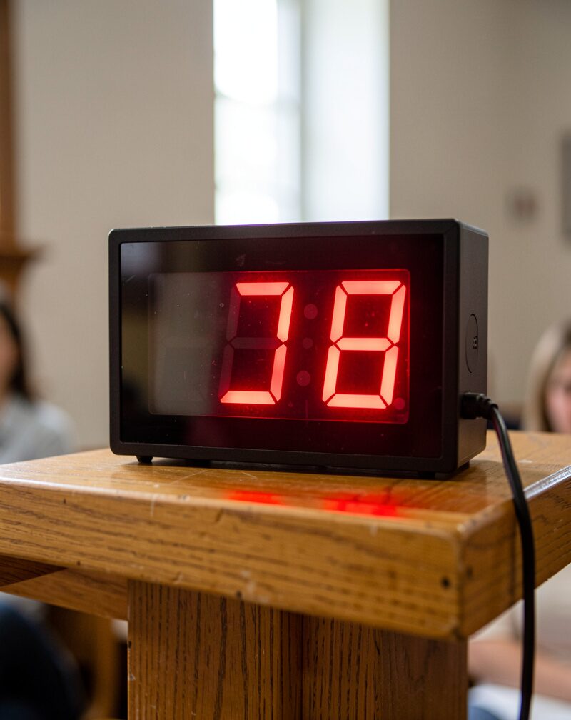 A red illuminated timer on a lectern showing two minutes remaining